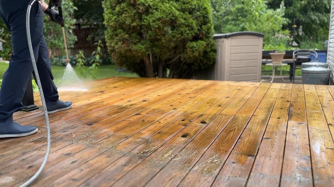 WashCrafters technician pressure washing a backyard deck