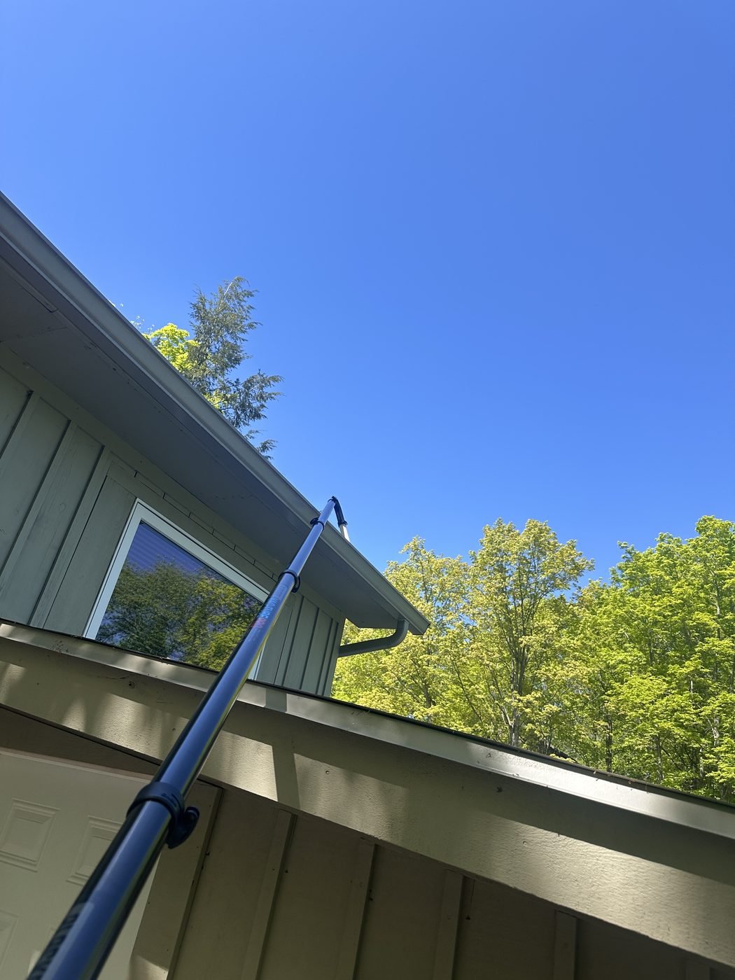 Gutter vacuum reaching a rooftop for debris removal
