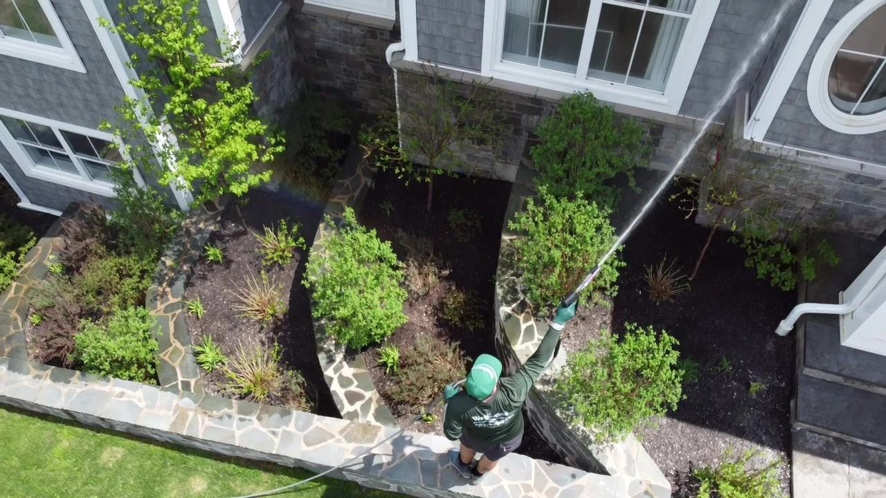 Aerial drone view of a WashCrafters technician soft washing a home exterior in Halifax, NS